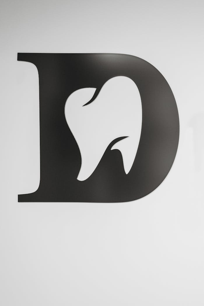 Simple black and white tooth design within letter D, ideal for dental branding.